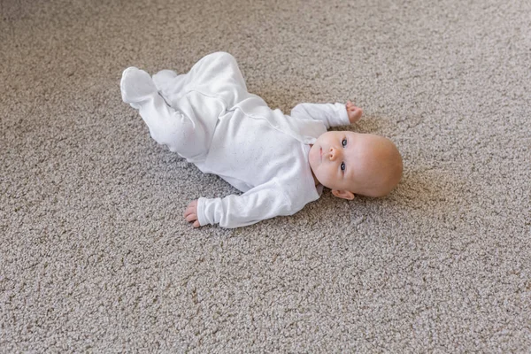 Концепция детства, младенцев и людей - маленький ребенок лежит на полу — стоковое фото