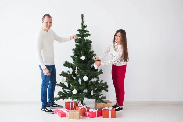 Vacaciones de invierno y el concepto de la gente - pareja amorosa colgando decoraciones en el árbol de Navidad — Foto de Stock
