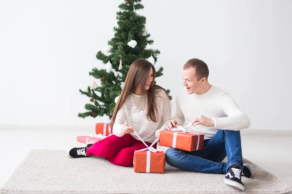Dulce pareja abriendo regalos de Navidad, sentado en la sala de estar . — Foto de Stock
