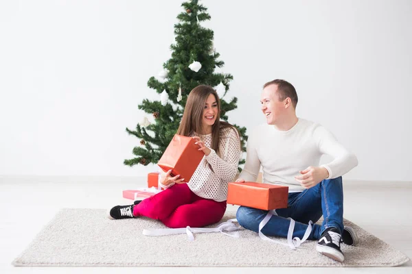 Dulce pareja abriendo regalos de Navidad, sentado en la sala de estar . — Foto de Stock