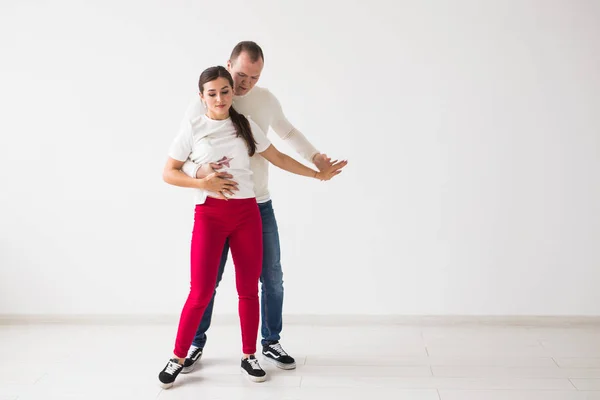 Casal feliz dançando dança social kizomba vs bachata ou salsa ou zouk no fundo claro — Fotografia de Stock