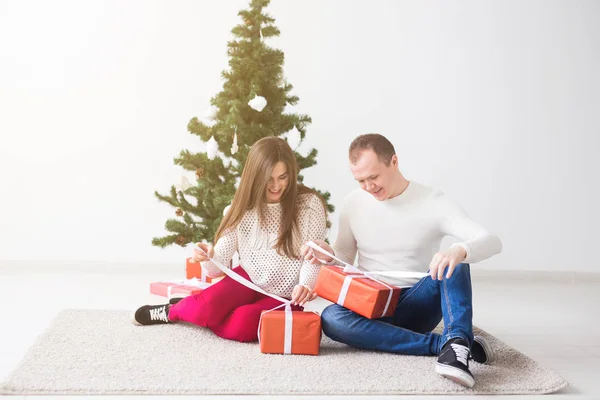 Vacaciones y concepto de Navidad - Sonriente pareja joven moderna abriendo regalos de Navidad — Foto de Stock
