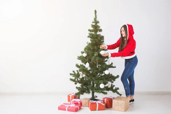 Férias de inverno, xmas e conceito de pessoas - Mulher bonita decorando uma árvore de Natal na sala branca com espaço de cópia — Fotografia de Stock