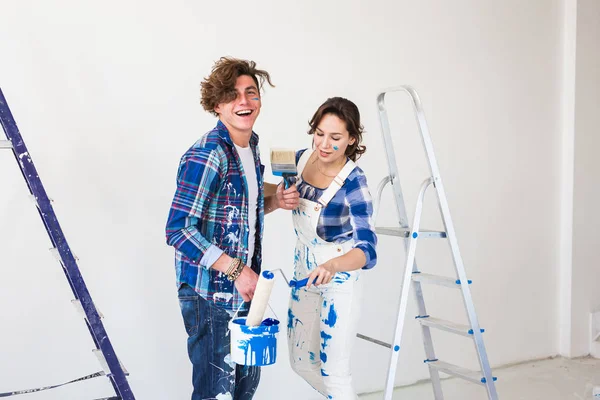 Personnes, concept de réparation et de relation - Jeune couple drôle faisant des rénovations dans un nouvel appartement — Photo