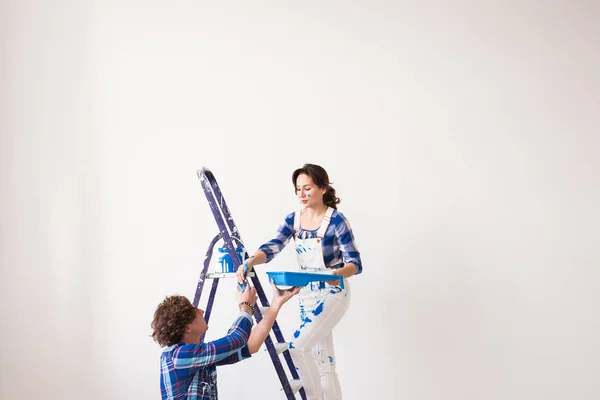 Familia, renovación, felicidad y concepto de redecoración - familia joven haciendo reparación, pintando paredes juntos — Foto de Stock