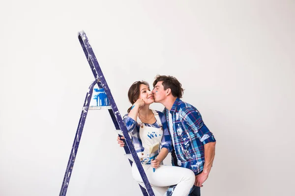 Pessoas, renovação e reparação conceito - jovem casal fazendo uma redecoração e beijando em novo apartamento — Fotografia de Stock