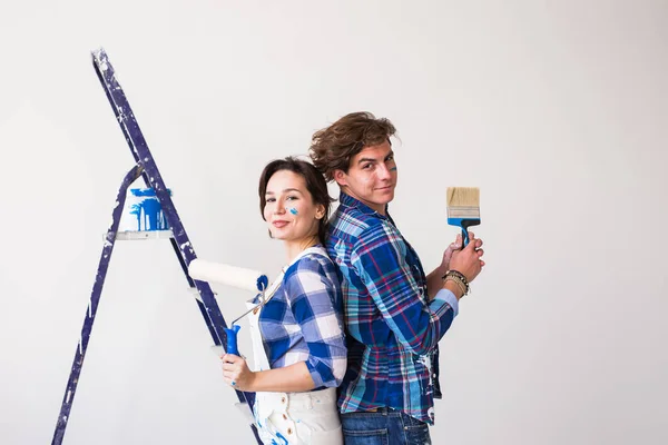 Trabajo en equipo, concepto de reparación y renovación - Hombre y mujer cubiertos de pintura en un apartamento nuevo — Foto de Stock
