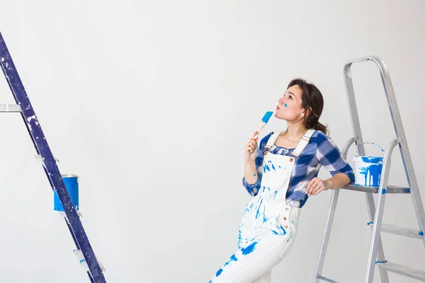 Gente, renovación y concepto de trabajo - Hermosa mujer de pie con escalera y paredes de pintura — Foto de Stock