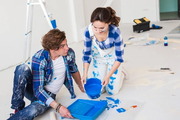 Riparazione, ristrutturazione e concetto di persone - coppia andando a dipingere il muro, stanno preparando il colore — Foto Stock