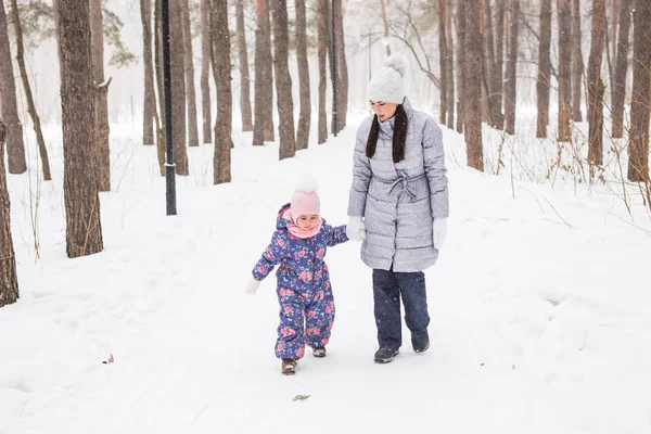 Motherhood, children and nature concept - Attractive young woman and adorable child walking in park — Stock Photo, Image