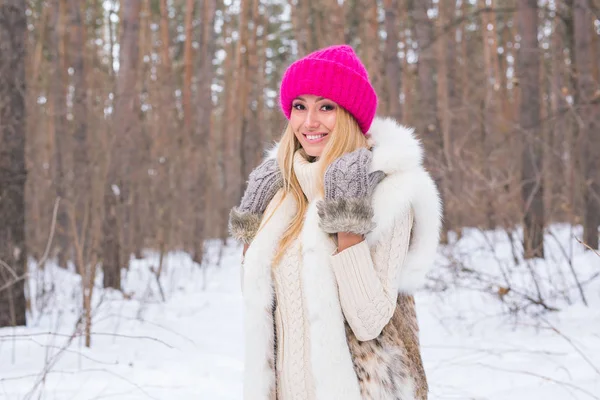 Краса, зима і концепція людей - приваблива блондинка в рожевому светрі в засніженому лісі посміхається — стокове фото