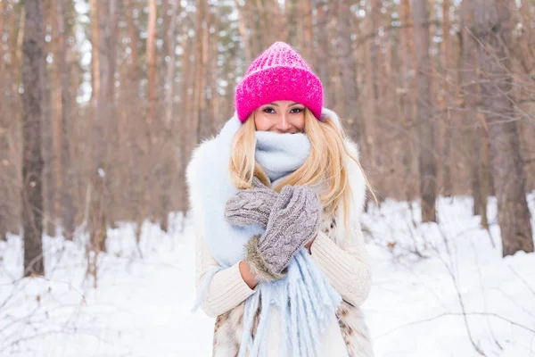 Concept mode et personnes - Portrait d'une jolie jeune femme blonde vêtue d'un manteau blanc et d'un chapeau rose dans un parc enneigé d'hiver — Photo