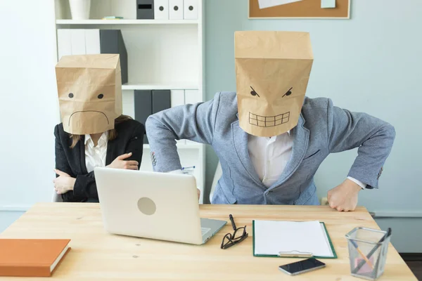 Business, emotions and people concept - Two angry and exhausted workers at working place. People wearing the packages on their heads with pictured emotions