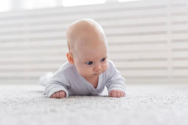 Childhood, babyhood and people concept - little baby boy or girl crawling on floor at home — Stock Photo, Image