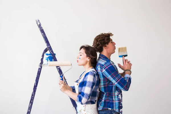 Ekip çalışması, onarım ve yenileme kavramı - erkek ve kadın yeni daire boya kaplı — Stok fotoğraf