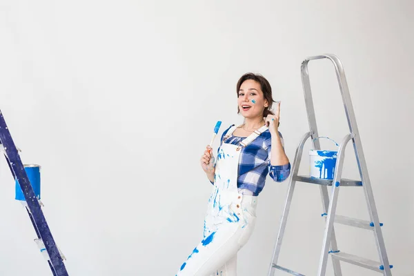 Gente, renovación y concepto de trabajo - Hermosa mujer de pie con escalera y paredes de pintura — Foto de Stock