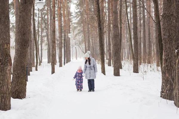 Inverno, infância e conceito de pessoas - a mãe está andando com sua filhinha na floresta nevada — Fotografia de Stock