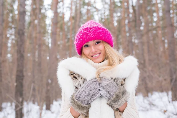 Divat, és az emberek koncepció - öltözött fehér szőrzet és a rózsaszín kalapot a téli havas park vonzó fiatal szőke nő portréja — Stock Fotó
