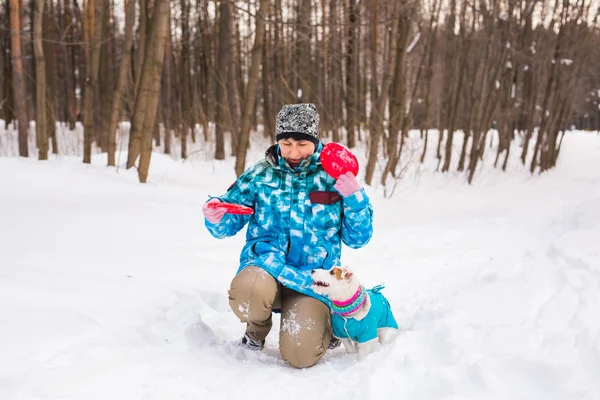 Propietario de mascotas y concepto de invierno - Mujer de mediana edad jugando con su perro jack russell terrier en el parque cubierto de nieve . — Foto de Stock