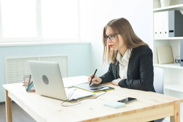 Concept de travail, d'entreprise, de technologie et de designer - jeune femme utilisant une tablette et regardant dans un ordinateur portable — Photo