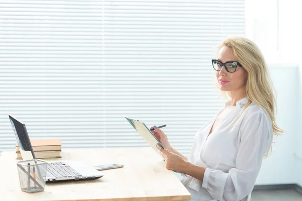 Arbeit, Wirtschaft, Technologie und Menschen-Konzept - junge Frau schreibt Notizen und lächelt — Stockfoto