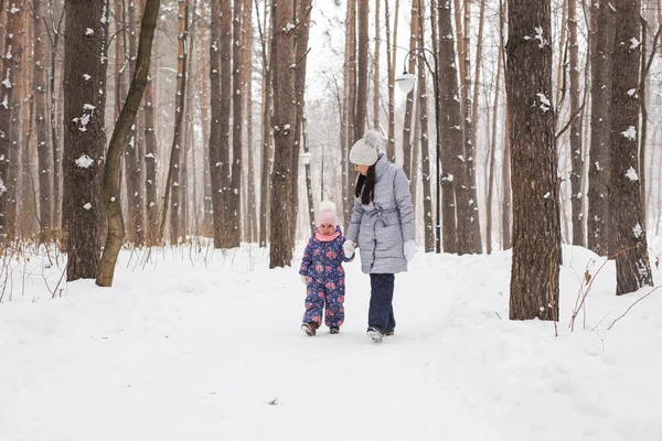 Gelukkige familie moeder en kind dochter hebben plezier, spelen in de winter wandeling buiten — Stockfoto