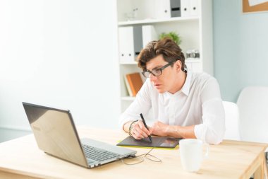 İş, tasarım ve insanlar kavramı - beyaz gömlekli grafik tablet ahşap masa kullanma yakışıklı genç