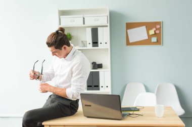 İnsanlar, eğlence ve iş kavramı - genç işadamı onun gözlük temizler.