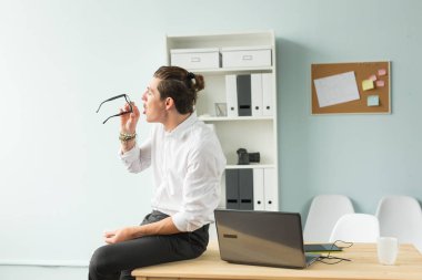 İnsanlar, eğlence ve iş kavramı - genç işadamı onun gözlük temizler.