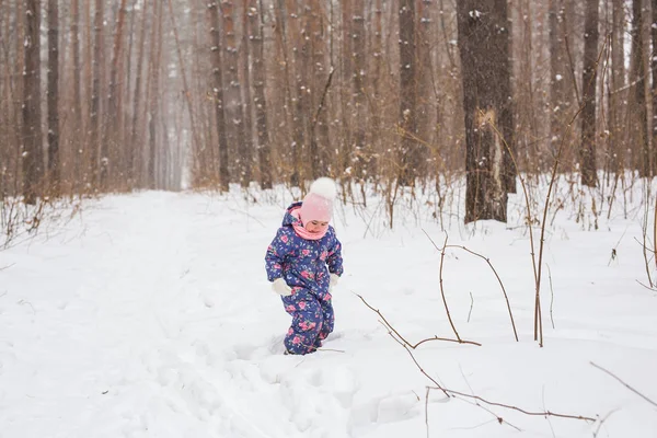 Концепция детства и детей - малышка гуляет зимой на свежем воздухе — стоковое фото