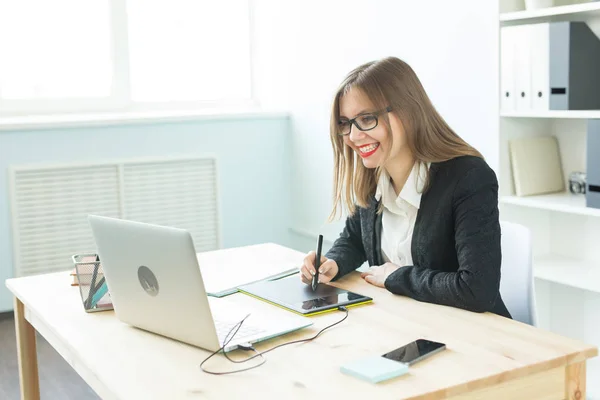 Concept de travail, d'entreprise, de technologie et de designer - jeune femme utilisant une tablette et regardant dans un ordinateur portable — Photo