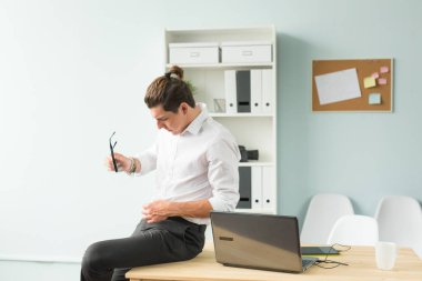 İş, mizah ve insanlar kavramı - Beyaz tişörtlü tahta masada oturan genç adam