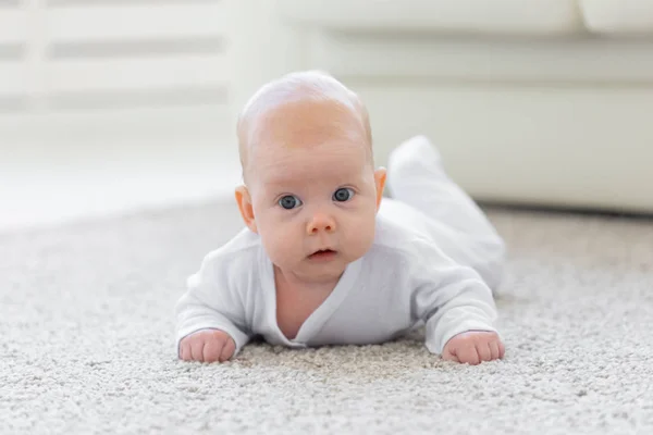 Baby, childhood, people concept - Portrait of a crawling baby on the floor