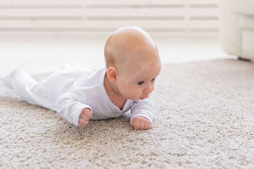 Childhood, babyhood and people concept - little baby boy or girl crawling on floor at home