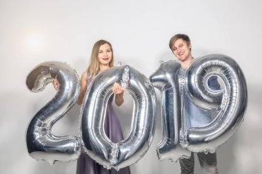 Yeni 2019 yılı önümüzdeki kavramı - mutlu genç adam ve kadın beyaz arka plan üzerinde gümüş renkli numaraları tutuyorsun