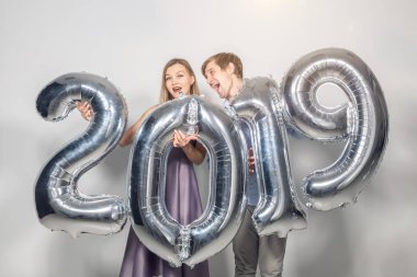 Yeni 2019 yılı önümüzdeki kavramı - mutlu genç adam ve kadın beyaz arka plan üzerinde gümüş renkli numaraları tutuyorsun