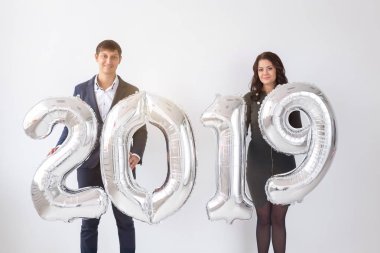 Yeni 2019 yılı önümüzdeki kavramı - mutlu genç adam ve kadın beyaz arka plan üzerinde gümüş renkli numaraları tutuyorsun