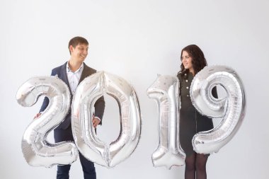 Yeni 2019 yılı önümüzdeki kavramı - neşeli genç adam ve kadın gümüş renkli numaraları tutuyorsun