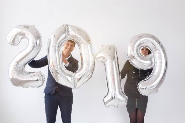 Yeni 2019 yılı önümüzdeki kavramı - neşeli genç adam ve kadın gümüş renkli numaraları tutuyorsun