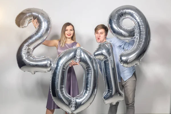 Nuovo 2019 Anno sta arrivando concetto - Felice giovane uomo e donna sono in possesso di numeri color argento su sfondo bianco — Foto Stock