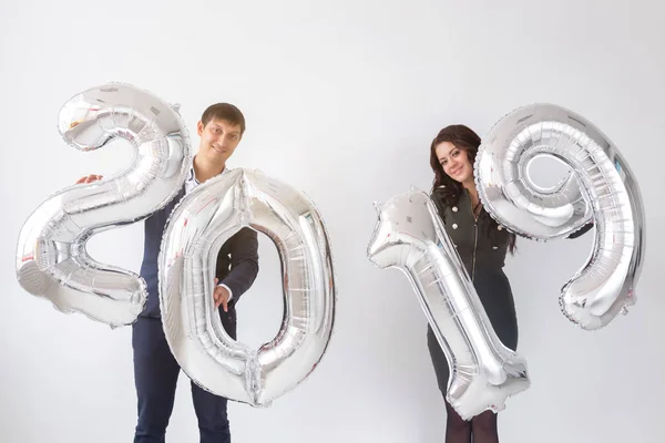 Nuevo 2019 Año viene concepto - Feliz joven hombre y mujer están sosteniendo números de color plata sobre fondo blanco — Foto de Stock