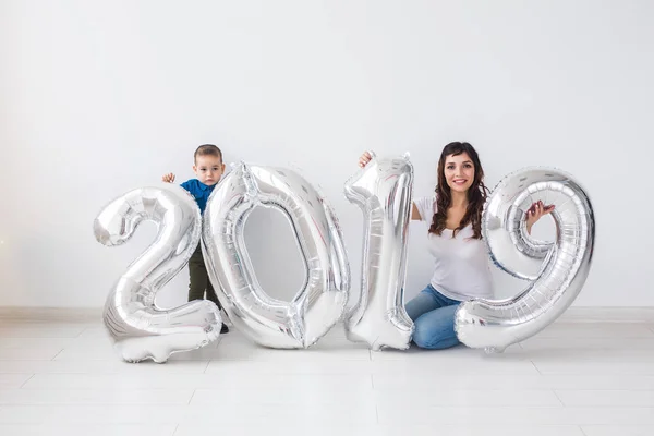 Nuevo 2019 Año viene concepto - Feliz madre e hijo con números de color plata en el interior . —  Fotos de Stock