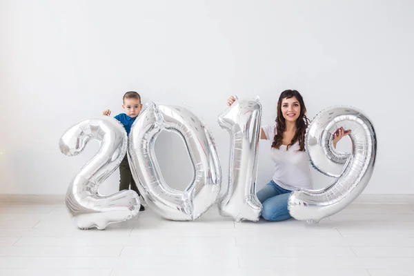 Nuevo 2019 Año viene concepto - Feliz madre e hijo con números de color plata en el interior . — Foto de Stock