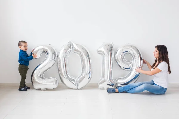 Nuevo 2019 Año viene concepto - Alegre madre e hijo pequeño con números de color plata en el interior . — Foto de Stock