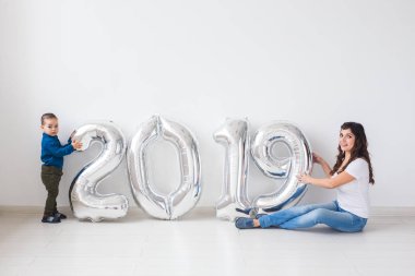 Yeni 2019 yıl önümüzdeki - gümüş renkli numaraları kapalı oturan bebek oğlu ile annesi bir kavramdır.