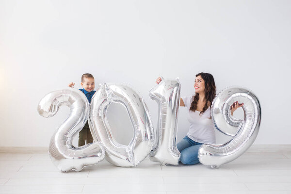 New 2019 Year is coming concept - Cheerful mother and little son with silver colored numbers indoors.
