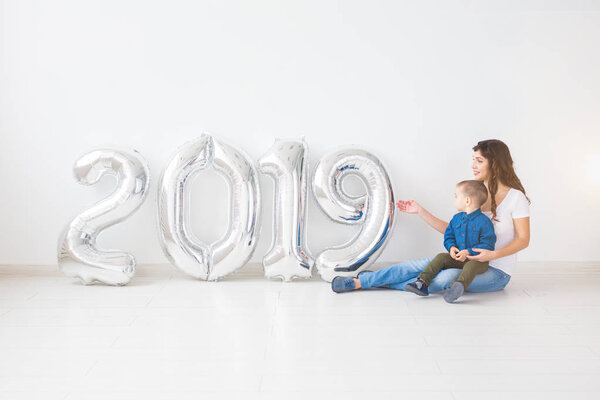 New 2019 Year is coming concept - Cheerful mother and little son with silver colored numbers indoors.