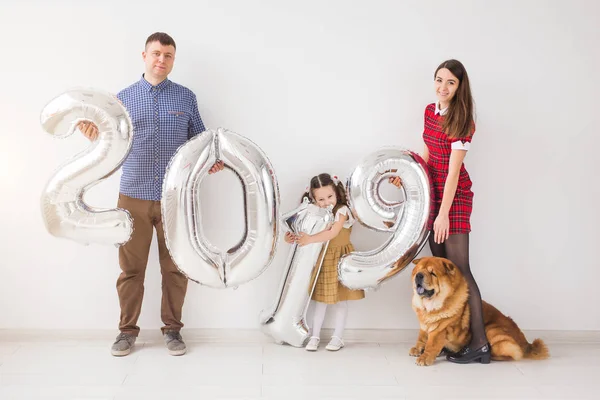 Ano Novo, celebração e feriados conceito - família segurando sinal 2019 feito de balões de prata para o ano novo no fundo da sala branca — Fotografia de Stock