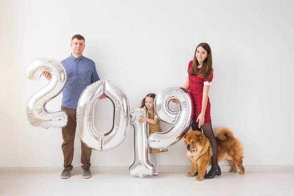 Nuevo 2019 Año viene concepto - Familia feliz con perro están sosteniendo números de color plata en el interior . — Foto de Stock