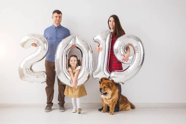 Nuevo 2019 Año viene concepto - Alegre madre, padre, hija y perro están sosteniendo números de color plata en el interior . —  Fotos de Stock